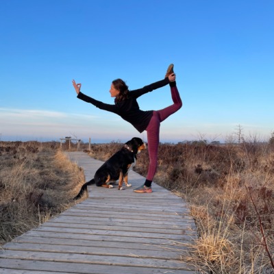 woman in blue tank top and blue leggings standing on gray rock near river during daytime